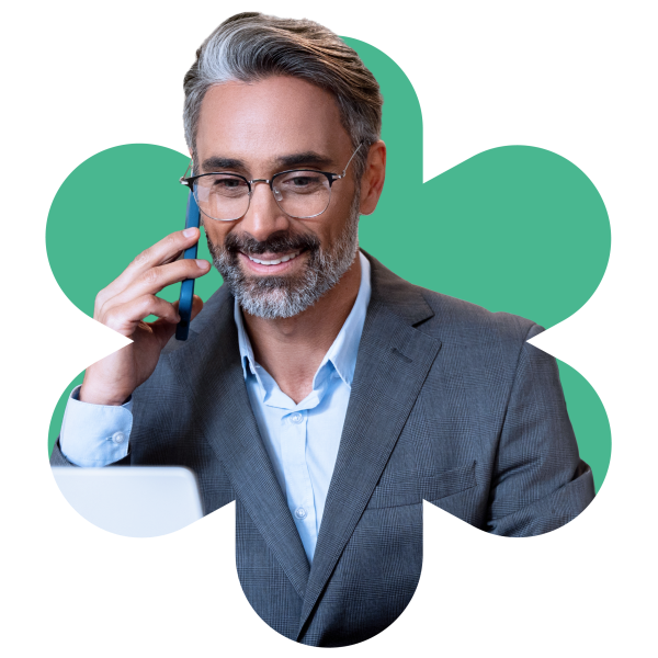 A man in a suit and glasses speaks on the phone, representing Bullhorn Automation for staffing agency solutions.